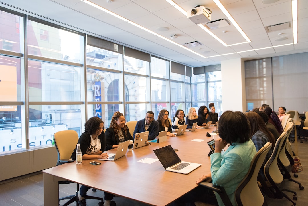 Group meeting at a conference table with laptops — representing department chair involvement in accreditation