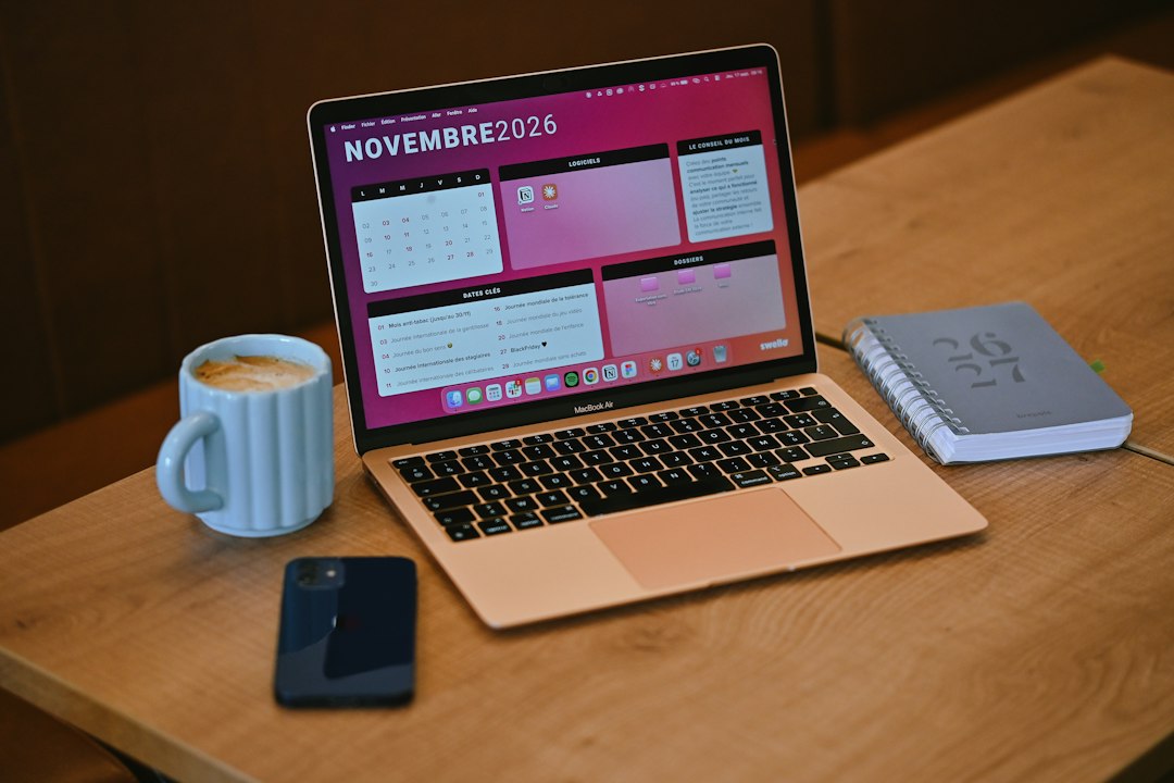 A laptop showing a November 2026 calendar next to a coffee mug, smartphone, and notebook on a wooden desk