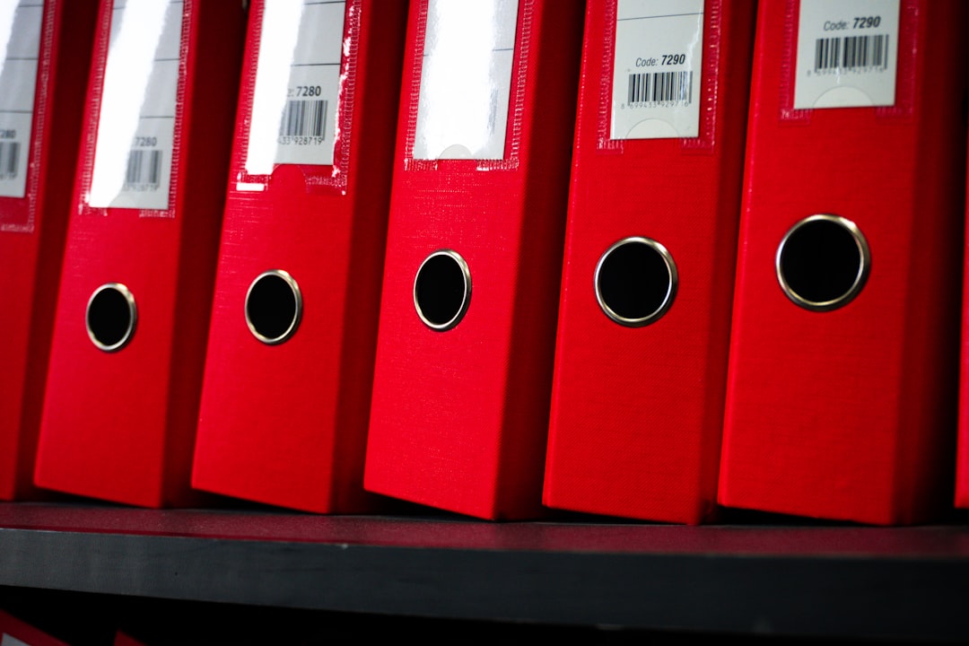 Row of red accreditation evidence folders lined up on a shelf, representing accumulated documentation