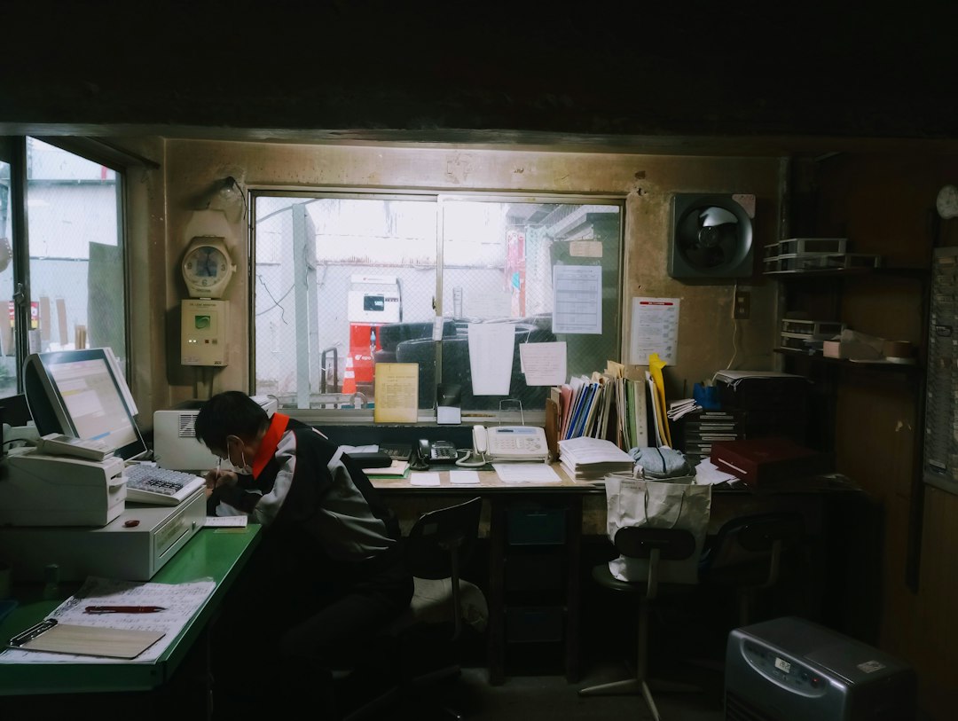 A coordinator working at a cluttered desk full of open files